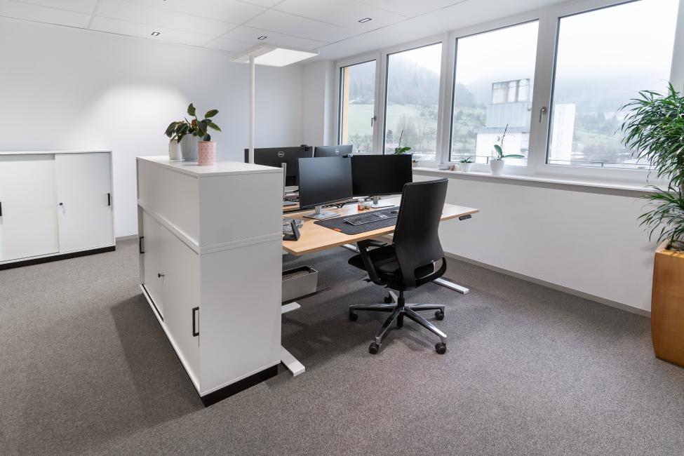 Ein Büro mit Tischen, Stühlen und Regalen